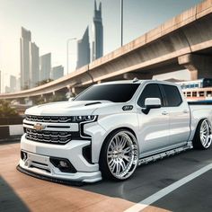 a white truck is driving down the road in front of a bridge and cityscape