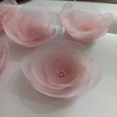 four pink flowers with pearls on them sitting on a white counter top in front of a mirror