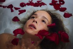 a woman laying in a bath filled with rose petals