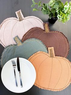 a white plate topped with a fork and knife next to three pumpkin shaped placemats