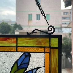 a stained glass window with a blue bird on it's side and a building in the background