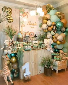 a baby's first birthday party decorated with balloons and jungle animals, including giraffes