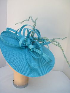 "* This design can be worn on either side of the head and has a sophisticated side tilt. It features a monocromatic color scheme in a tantalizing turquoise. The center of the hat form has a burst of looped and swirled braiding accented by enhanced clusters of matching berries and curly berry twigs. * On an 12\" round flat hat form this is a great design for spring and summer and will also go right into the fall and winter as well. * It is light weight, balanced and comfortable on a white satin c Blue Fitted Fascinator For Beach, Turquoise Fascinator For Kentucky Derby, Elegant Turquoise Fascinator For Kentucky Derby, Elegant Turquoise Fascinator For Wedding, Turquoise Fitted Party Hat, Turquoise Fitted Hat For Party, Fitted Turquoise Hat For Party, Spring Turquoise Fitted Fascinator, Turquoise Fascinator For Spring Party