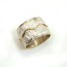 This is a wide, bold ring, chunky but not heavy, that makes a statement. It has a crumpled tinfoil texture with a wavy gold stripe soldered on top. Width: 0.56 inch / 14 mm Thickness: 0.1 inch / 2.5 mm This listing is for sizes 4-13- Just convo me your size. For other sizes - please convo me. Additional information If you liked this item, you may also want to look at these pieces: http://etsy.me/2fWkafJ http://etsy.me/2eI2vT3 For customer reviews of our shop: http://etsy.me/2eOQZZt Back to our s Unique Hammered Rings With Thick Band, Unique Hammered Wide Band Rings, Elegant Wide Band Hand Cast Jewelry, Hand Cast Silver Wide Band Ring, Elegant Hand Cast Wide Band Jewelry, Hand Forged Wide Band Ring As Gift, Hand Forged Wide Band Ring For Gift, Hand Forged Thick Band Wide Ring, Wide Band Silver Hammered Jewelry