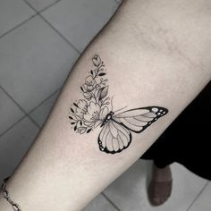 a black and white butterfly with flowers on the arm