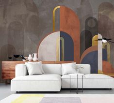 a white couch sitting in front of a wall with abstract paintings on it's walls