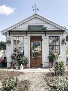 a small white building with potted plants outside