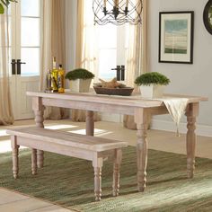 a dining room table and bench in front of a window with potted plants on it