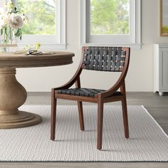 a wooden chair sitting in front of a table with flowers on it and a vase