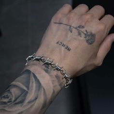 a person with a tattoo on their arm holding onto a chain bracelet that has a rose tattooed on it