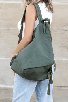 a woman carrying a large green bag on her back while standing in front of some steps