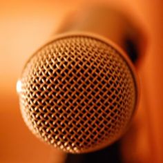 a close up view of a microphone on a wooden table with an orange wall in the background