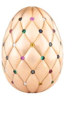 an egg with many colored stones on it's side, sitting in front of a white background