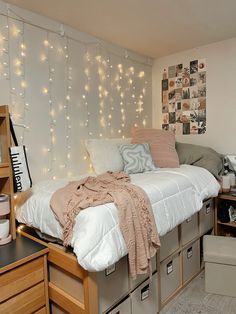 a bed with lots of lights on the wall above it and some drawers underneath it