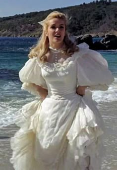 a woman in a white dress standing on the beach