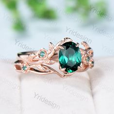 a ring with an oval green stone surrounded by vines and leaves on top of it