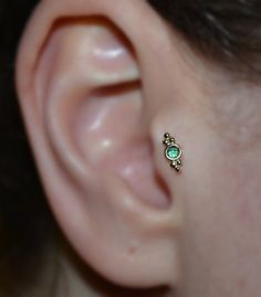 a close up of a person's ear with a green stone in the middle