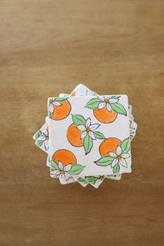 four oranges with leaves and flowers on them are sitting on top of a wooden table