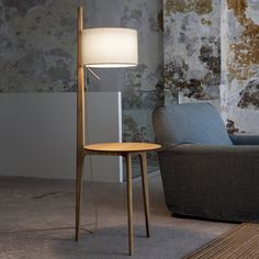 a floor lamp sitting on top of a wooden table next to a chair and ottoman