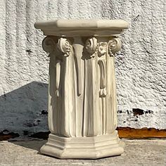 a white vase sitting on top of a sidewalk