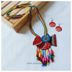 a colorful necklace and earring set sitting on a table next to a wooden box