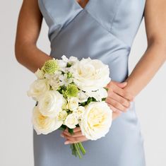 a woman in a blue dress holding a bouquet of white flowers