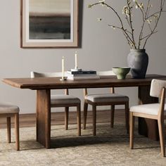 a dining room table with chairs and a vase filled with flowers on top of it