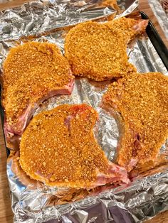 four pieces of meat sitting on top of tin foil covered in seasoning and toppings