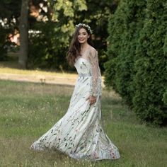 a woman in a white dress is standing in the grass wearing a floral headpiece