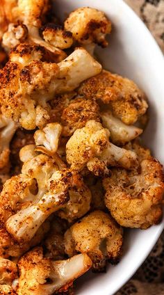 a white bowl filled with cooked cauliflower on top of a lace table cloth