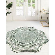 a green rug on the floor in front of a white door with a potted plant