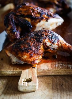 two pieces of chicken sitting on top of a wooden cutting board