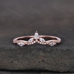 a rose gold engagement ring with two pear shaped diamonds on top and side stones around the band