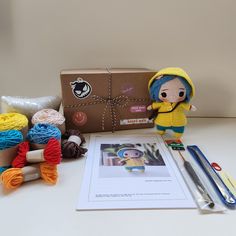 the doll is next to some yarn and crochet hooks on a table with scissors