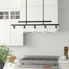 a kitchen with white cabinets and lights hanging from the ceiling over the stove top oven