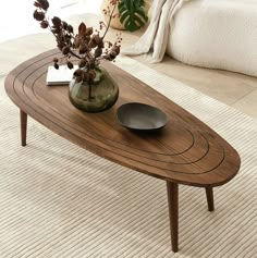 a wooden table sitting on top of a carpeted floor next to a vase filled with flowers