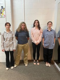 four young women standing in front of a wall with their hands on their hipss