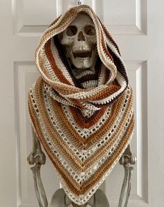 a skeleton wearing a crocheted shawl on top of a white door frame