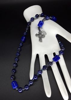 The Deep Blue Irish Anglican Rosary is a beautiful rosary that radiates the seven seas and provides you with a calming effect while praying. The rosary is made of Swarovski Crystals, Lapis lazuli and Jade gemstones (which have been cleansed and purified) while a Stainless Silver Cross completes the rosary. Finally, the rosary has been blessed by the church. Rosary: Anglican configuration Blessed: Yes About the Rosary: The Rosary has a Cross, an Invitatory bead, 4 sets of 7 beads that are called Blue Spiritual Cross Jewelry, Blue Cross Spiritual Jewelry, Blue Crucifix Necklace For Spiritual Wear, Blue Crucifix Necklace For Spiritual Purposes, Handmade Blue Crucifix Jewelry, Blue Rosary With 8mm Beads For Healing, Blue Spiritual Rosary With Gemstone Beads, Spiritual Blue Rosary With Gemstone Beads, Blue Gemstone Beads Rosary For Spiritual Use