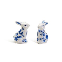 two blue and white rabbits sitting next to each other on top of a white surface