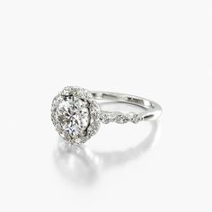 a white gold ring with an oval diamond in the center and pave set shoulders