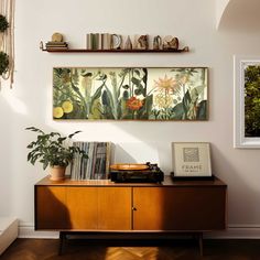 an old radio sits on top of a wooden cabinet in front of a wall with plants and books