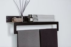 a black shelf with towels and candles on it next to a wall mounted towel rack