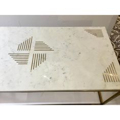 a white marble coffee table with gold lines on the top, and an intricately designed design