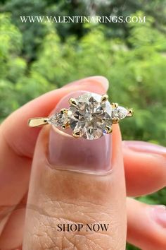 a woman's hand holding an engagement ring with three stones on the top and bottom