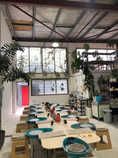 a long table with blue plates on it in a room filled with potted plants