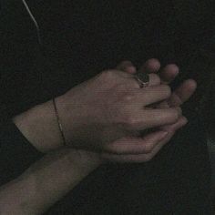 two hands holding each other in the dark with their fingers touching one another's hand