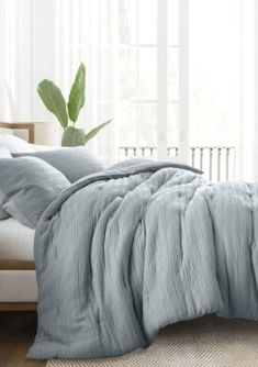 a bed with blue comforter and pillows in a room next to a white couch