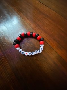 a red and black beaded bracelet sitting on top of a wooden table