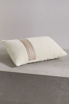 a white pillow sitting on top of a cement block next to a gray and brown wall